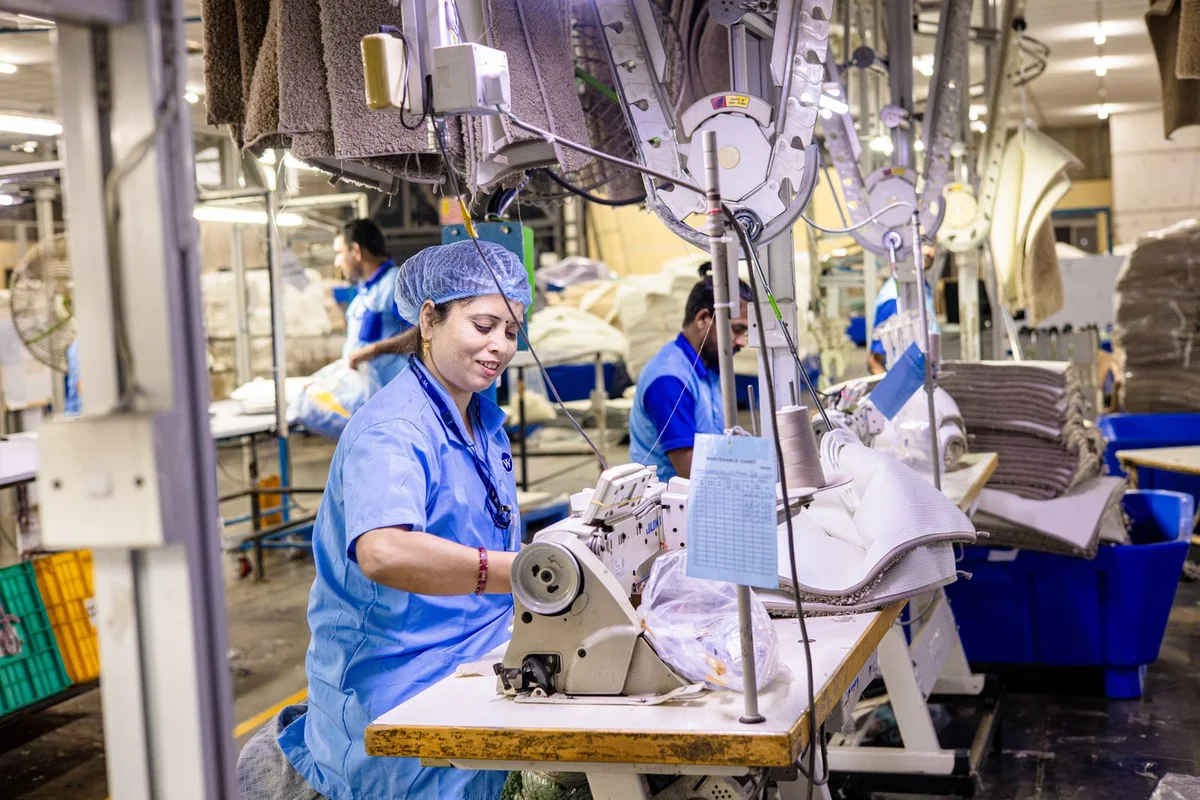 Textile factory workers operating sewing equipment during manufacturing quality review